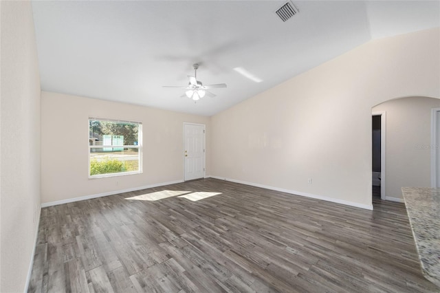 empty room featuring visible vents, a ceiling fan, wood finished floors, arched walkways, and vaulted ceiling