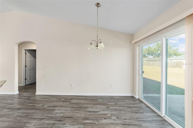 unfurnished dining area featuring arched walkways, baseboards, lofted ceiling, and wood finished floors