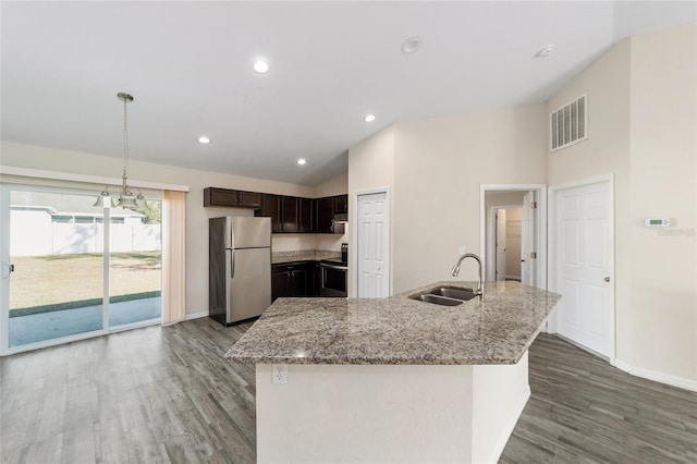 kitchen featuring light stone counters, wood finished floors, appliances with stainless steel finishes, and a sink