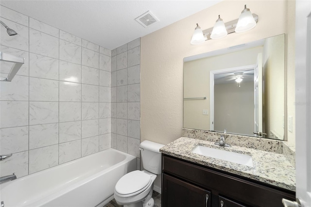 bathroom with visible vents, tub / shower combination, toilet, a textured wall, and vanity