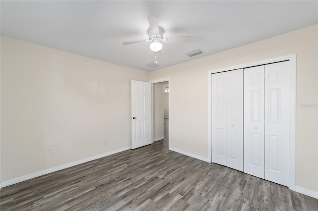 unfurnished bedroom featuring a closet, visible vents, baseboards, and wood finished floors