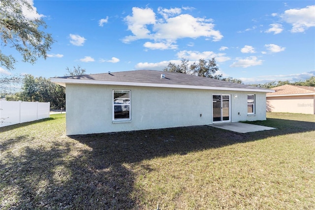 back of house featuring stucco siding, a yard, and fence