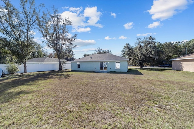 back of house with a yard, stucco siding, and fence