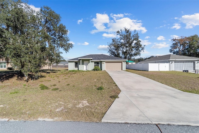 view of front of home with stucco siding, fence, concrete driveway, a front yard, and a garage