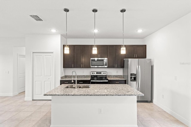 kitchen with appliances with stainless steel finishes, a kitchen island with sink, decorative light fixtures, light stone counters, and sink