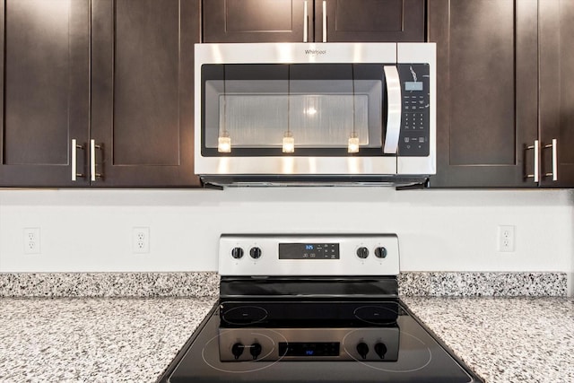 kitchen featuring appliances with stainless steel finishes, light stone counters, and dark brown cabinets