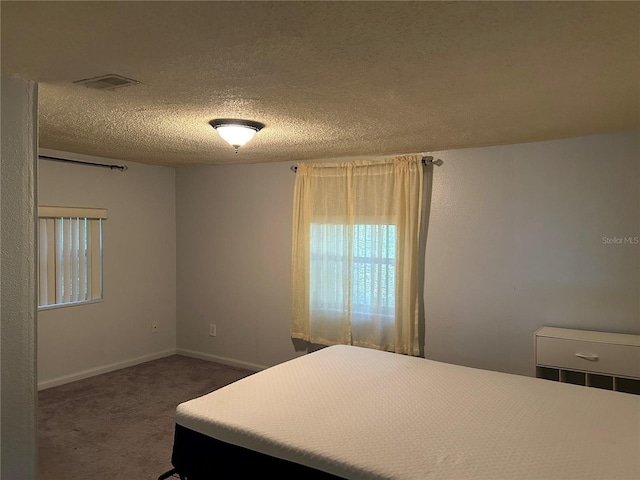 bedroom with dark carpet and a textured ceiling