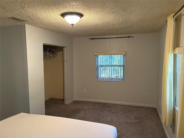 unfurnished bedroom with a closet, dark carpet, and a textured ceiling