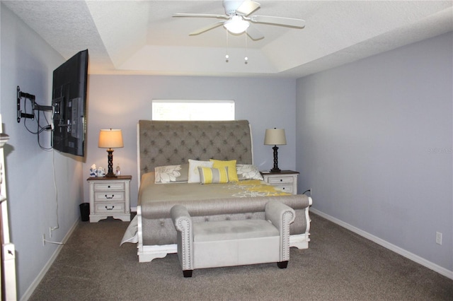 bedroom featuring a raised ceiling, ceiling fan, dark carpet, and a textured ceiling