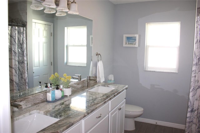 bathroom featuring wood-type flooring, vanity, toilet, and plenty of natural light