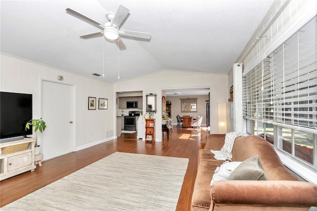 living room featuring ceiling fan, dark hardwood / wood-style flooring, lofted ceiling, and a textured ceiling