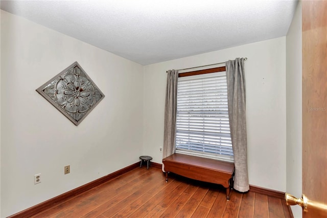 unfurnished room with hardwood / wood-style floors and a textured ceiling