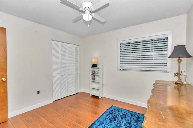 interior space with ceiling fan, wood-type flooring, a textured ceiling, and a closet