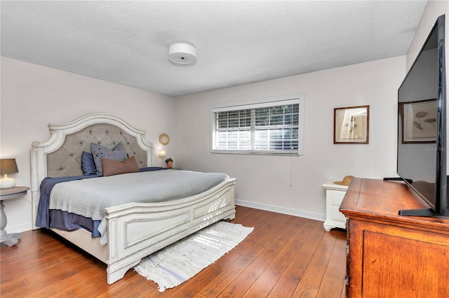 bedroom with a textured ceiling and dark hardwood / wood-style floors