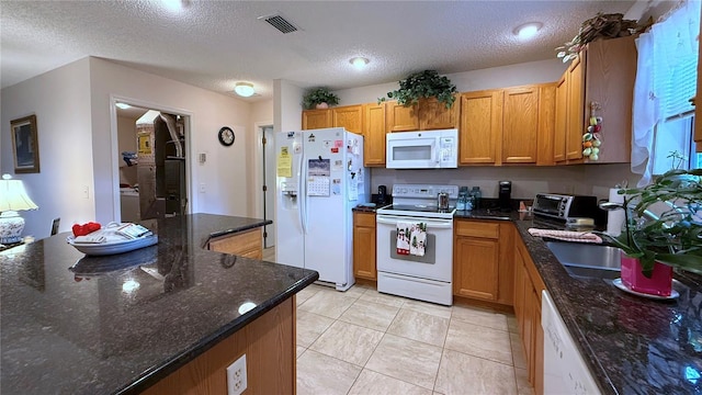 kitchen with white appliances, a textured ceiling, dark stone countertops, and light tile patterned floors