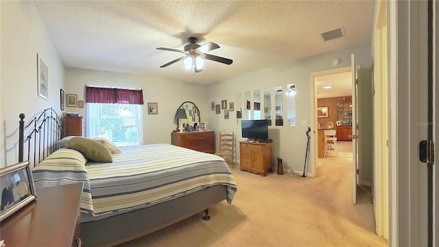 bedroom with ceiling fan, light carpet, and a textured ceiling