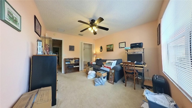 carpeted home office with a textured ceiling and ceiling fan