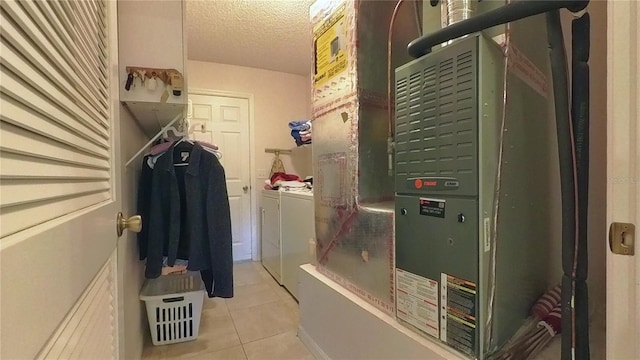 clothes washing area featuring a textured ceiling, washing machine and dryer, light tile patterned flooring, and heating unit