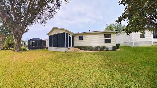 rear view of house featuring a lawn and a sunroom