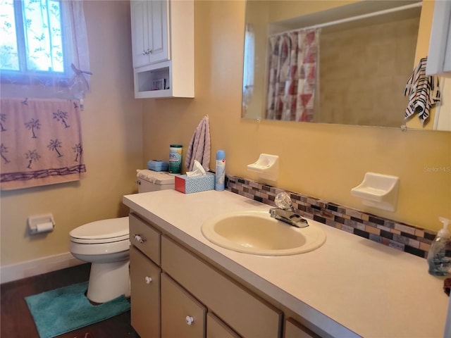 bathroom featuring vanity, toilet, and decorative backsplash