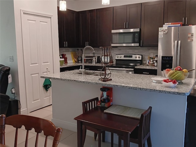 kitchen featuring light tile patterned floors, sink, stainless steel appliances, and dark brown cabinetry