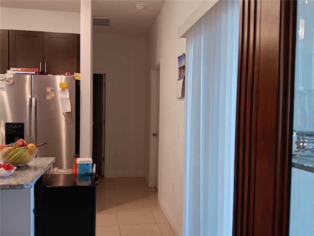 kitchen featuring light tile patterned floors, stainless steel refrigerator with ice dispenser, and dark brown cabinets