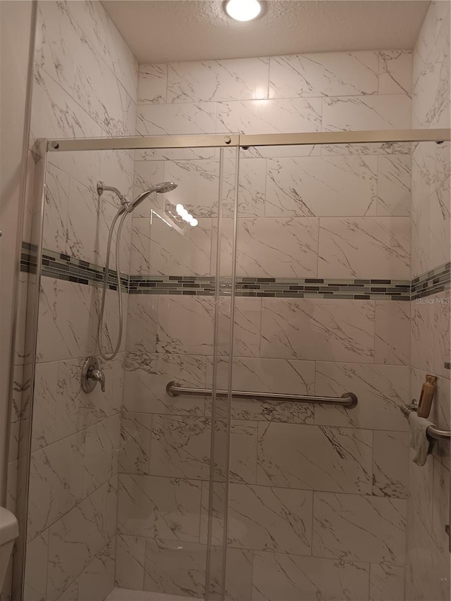 bathroom with walk in shower, toilet, and a textured ceiling