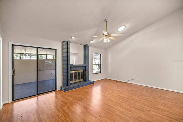 unfurnished living room with lofted ceiling, a brick fireplace, ceiling fan, and hardwood / wood-style floors