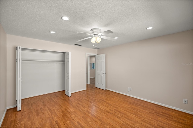 unfurnished bedroom featuring a textured ceiling, ceiling fan, light hardwood / wood-style floors, and a closet