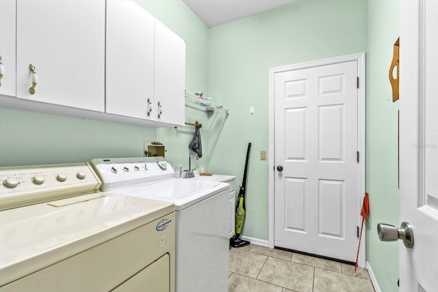 laundry area with washer and dryer, cabinets, and light tile patterned floors