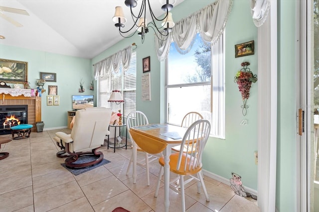 tiled dining room with vaulted ceiling and ceiling fan with notable chandelier