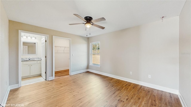 unfurnished bedroom with ceiling fan, ensuite bath, light wood-type flooring, a closet, and a walk in closet