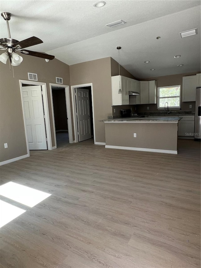 kitchen with white cabinetry, sink, vaulted ceiling, and pendant lighting