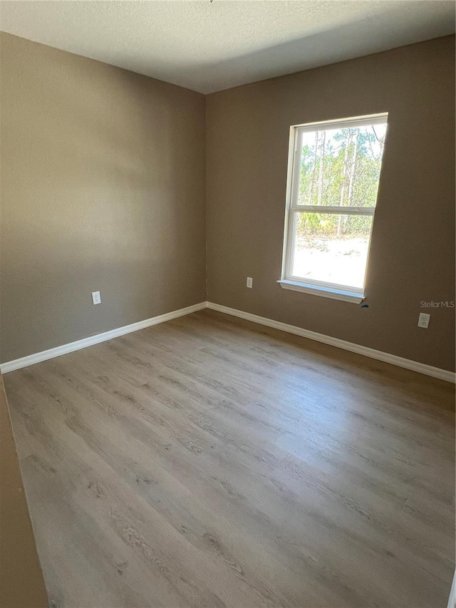 unfurnished room featuring light hardwood / wood-style flooring and a textured ceiling