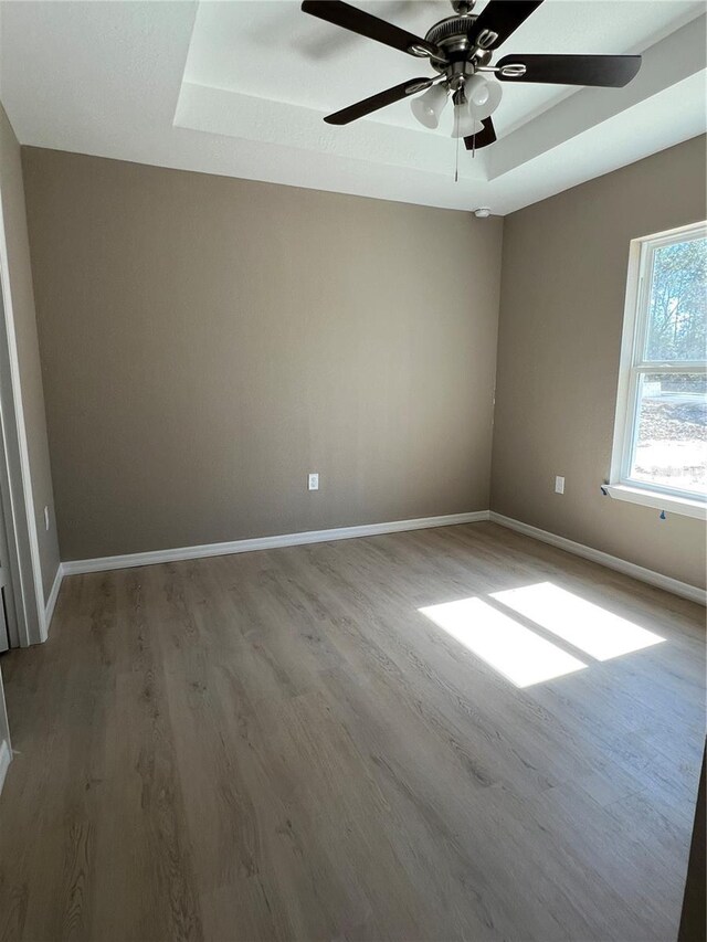 spare room featuring ceiling fan, wood-type flooring, and a raised ceiling