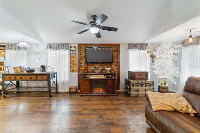 living room with dark wood-style floors, a glass covered fireplace, ceiling fan, and lofted ceiling