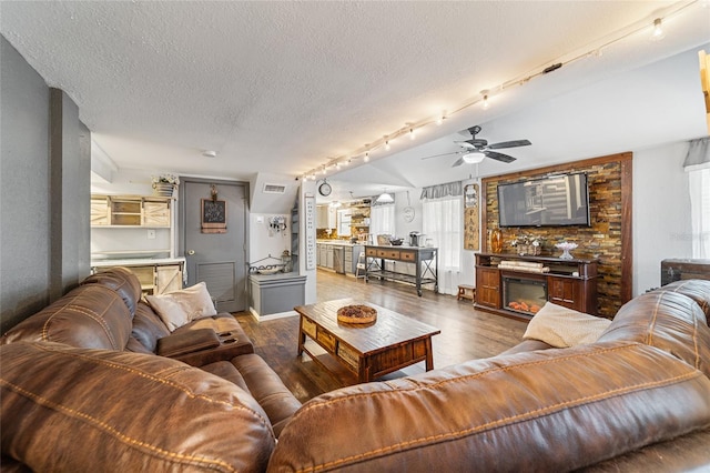 living area featuring a glass covered fireplace, dark wood-type flooring, rail lighting, and a textured ceiling