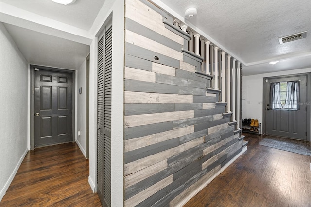 foyer featuring visible vents, a textured ceiling, wood-type flooring, baseboards, and stairs