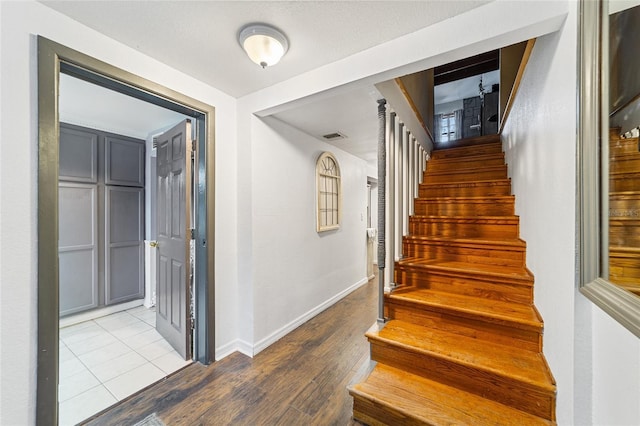 stairway featuring wood finished floors, visible vents, and baseboards