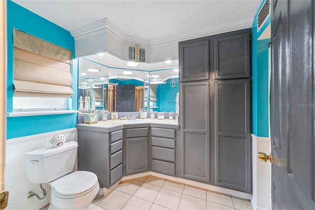 bathroom featuring tile patterned flooring, crown molding, toilet, wainscoting, and vanity