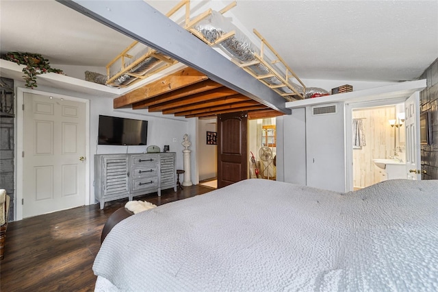 bedroom with visible vents, ensuite bath, lofted ceiling, and wood finished floors