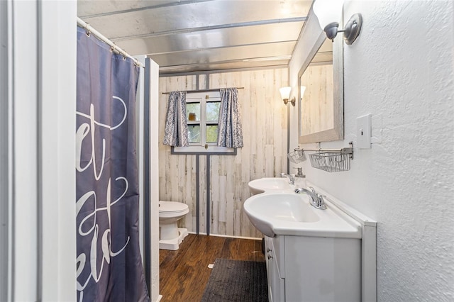 full bathroom with toilet, a sink, wood finished floors, a shower with shower curtain, and double vanity