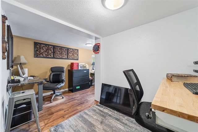 office with wood finished floors, baseboards, and a textured ceiling