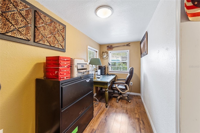 office space with hardwood / wood-style floors, a textured wall, baseboards, and a textured ceiling