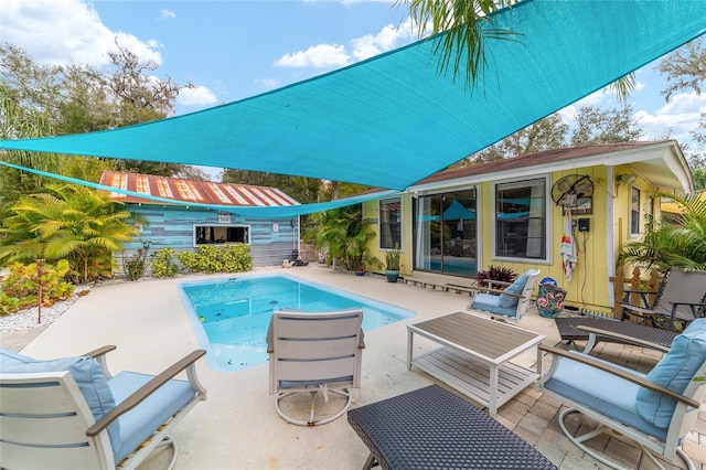 outdoor pool with an outbuilding, outdoor lounge area, and a patio