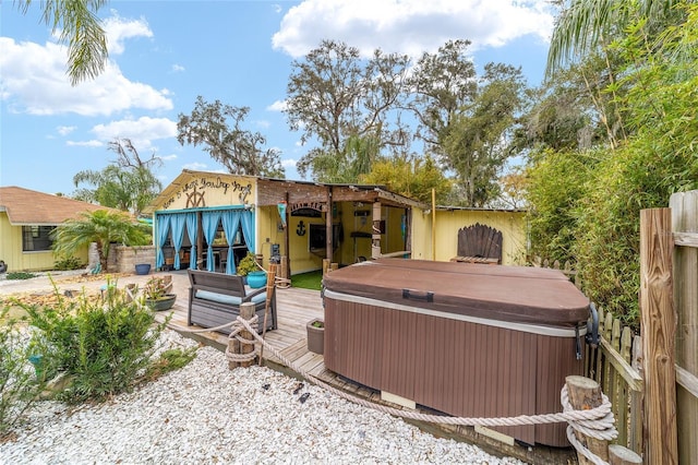 rear view of house featuring a wooden deck and a hot tub