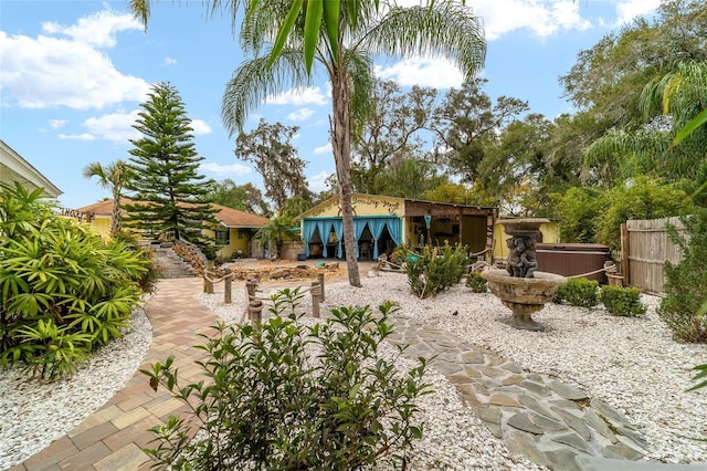 rear view of house with a hot tub and fence