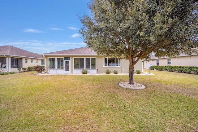 back of property featuring a sunroom and a lawn