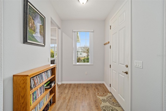 doorway to outside with a textured ceiling and light wood-type flooring