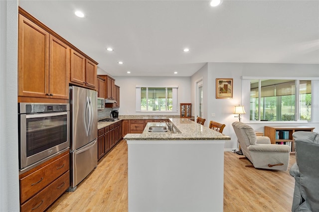 kitchen featuring light stone counters, stainless steel appliances, light hardwood / wood-style flooring, and sink